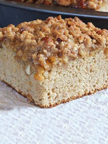 A slice of apple coffee cake served on parchment paper.