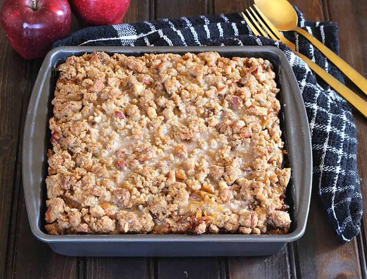 apple coffee cake with crumb topping served in a square 9 inch baking pan.