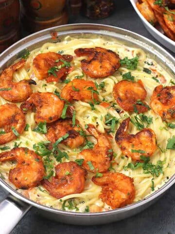 Top view of shrimp scampi with spaghetti pasta garnished with finely chopped cilantro.