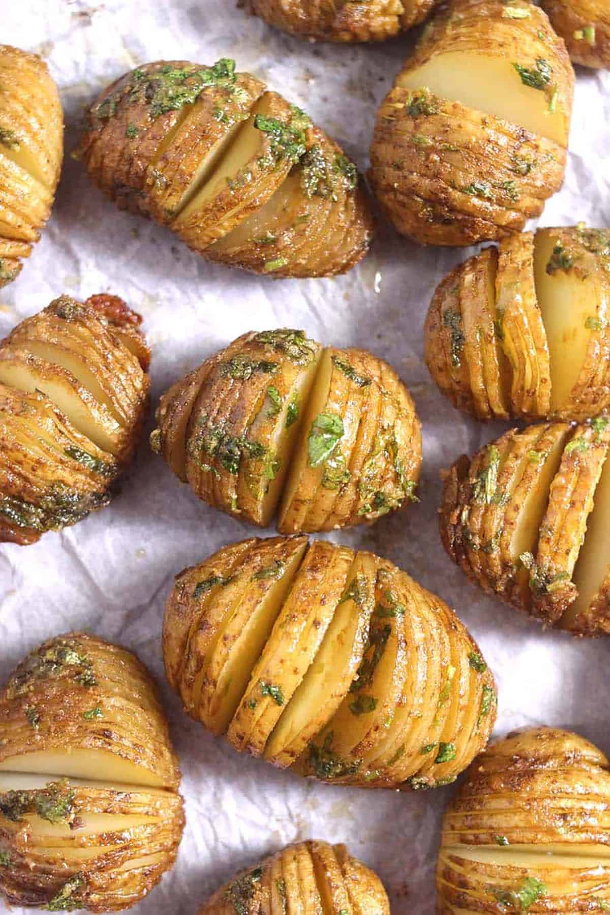 Top view of Hasselback Potatoes in a baking pan, flavored using herbed garlic butter.