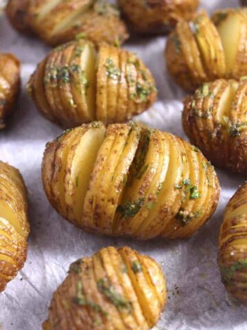 Top view of crispy garlic butter flavored Hasselback Potatoes in a baking pan.