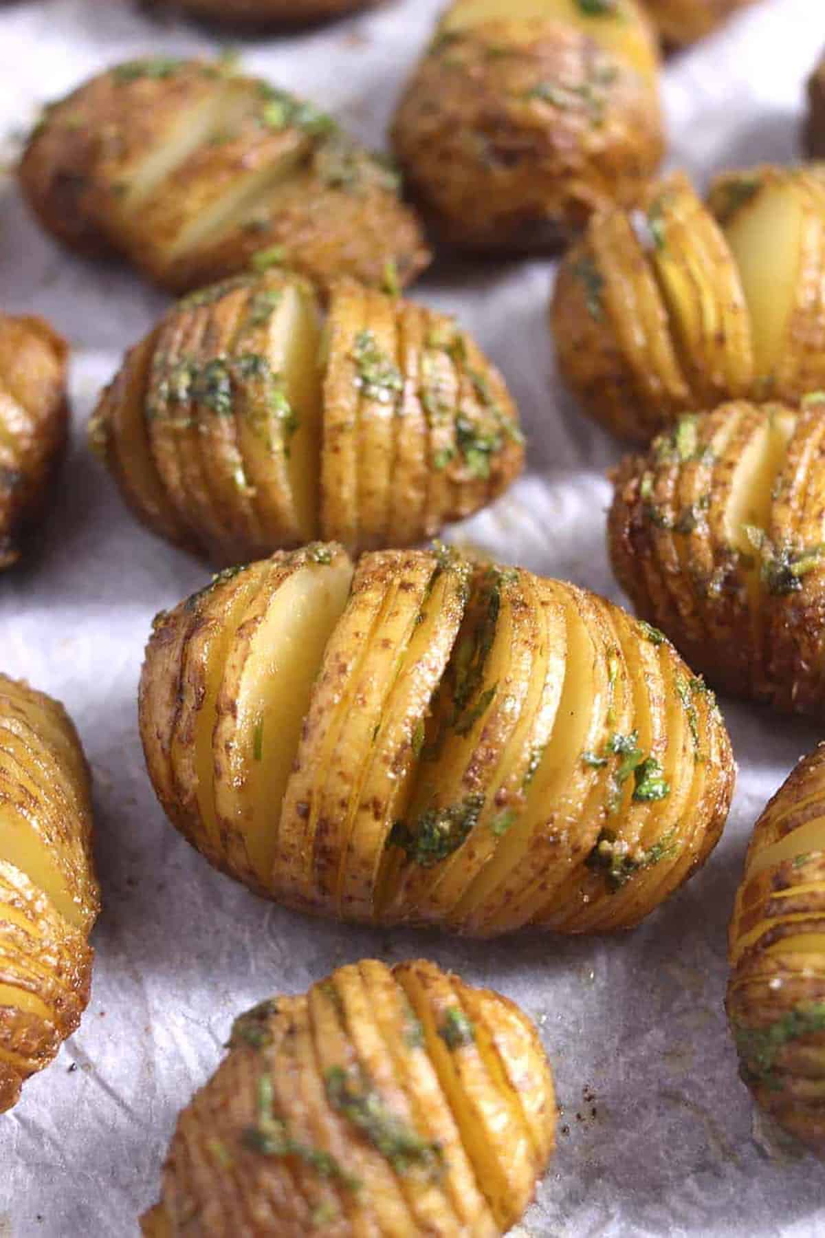 Top view of crispy garlic butter flavored Hasselback Potatoes in a baking pan.