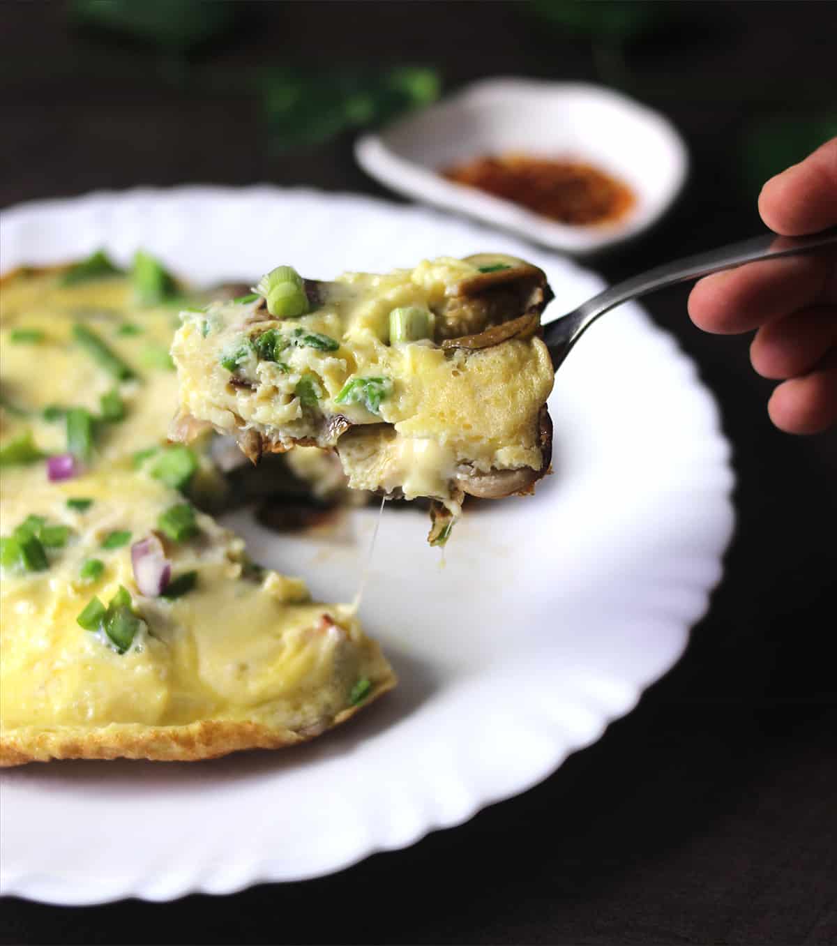 Holding keto cheese omelette (omlet) in a fork - best for weight loss, keto breakfast idea. 