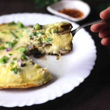 Best, quick and easy keto omelette served in white plate and lifted with fork.