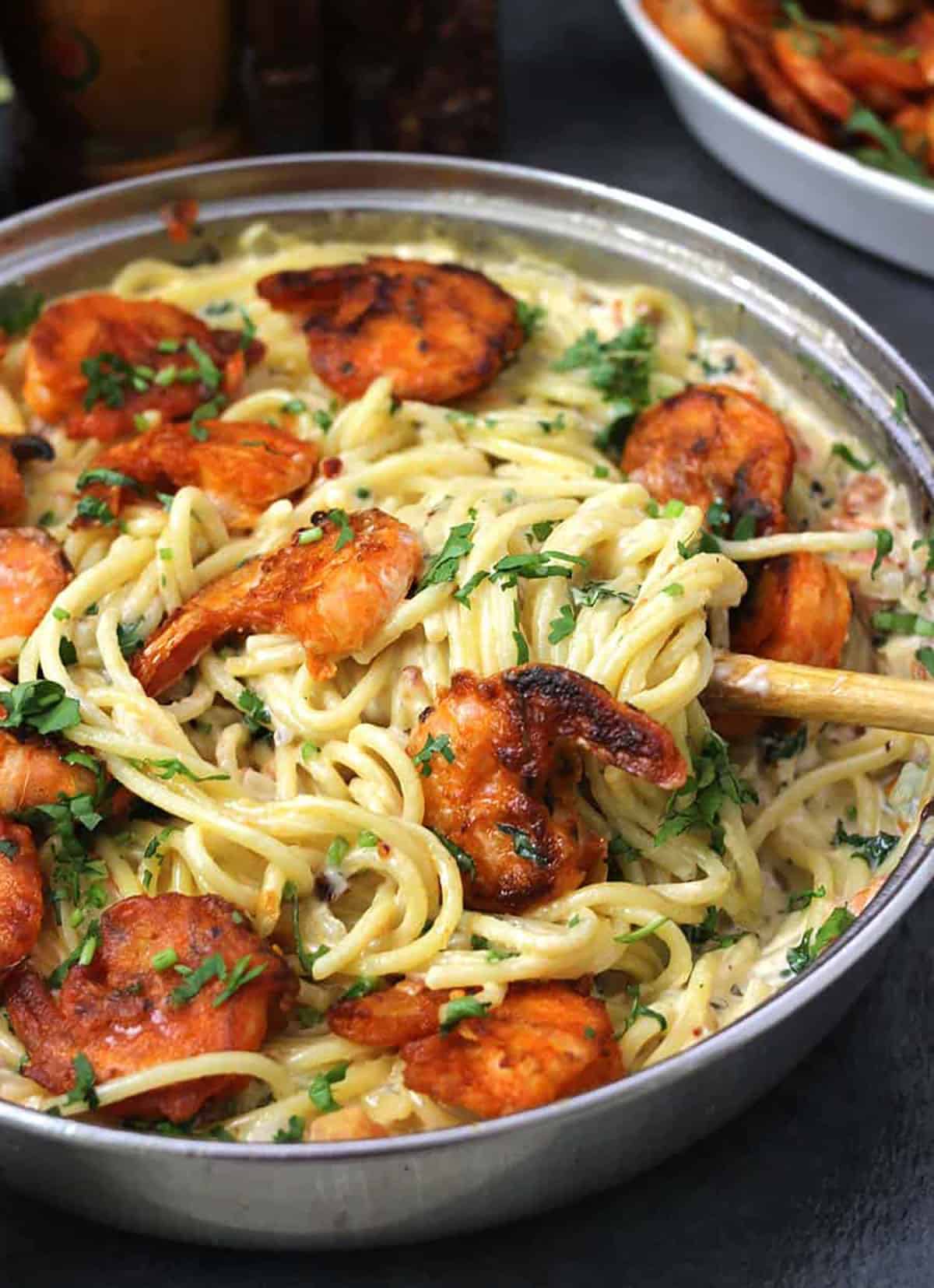 Bistro-style perfect shrimp scampi with linguini about to be served from a pan using wooden spatula.