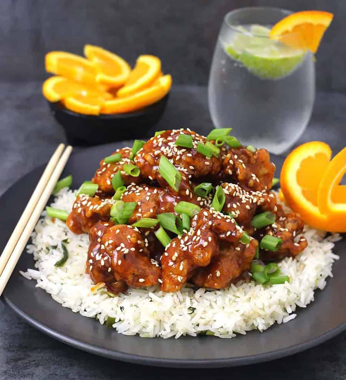 Orange chicken garnished with spring onions and toasted sesame seeds served over a bed of steamed rice. 