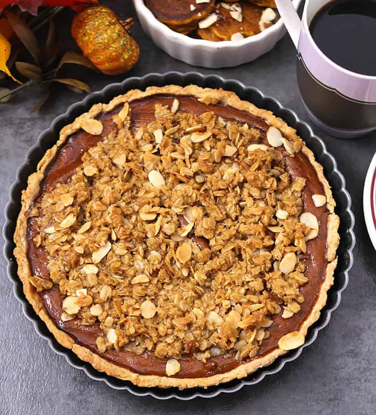 pumpkin pie with streusel topping just out of the oven in black pie pan.