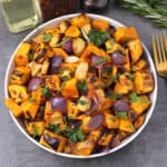 Roasted sweet potatoes garnished with fresh cilantro and presented in a white bowl.