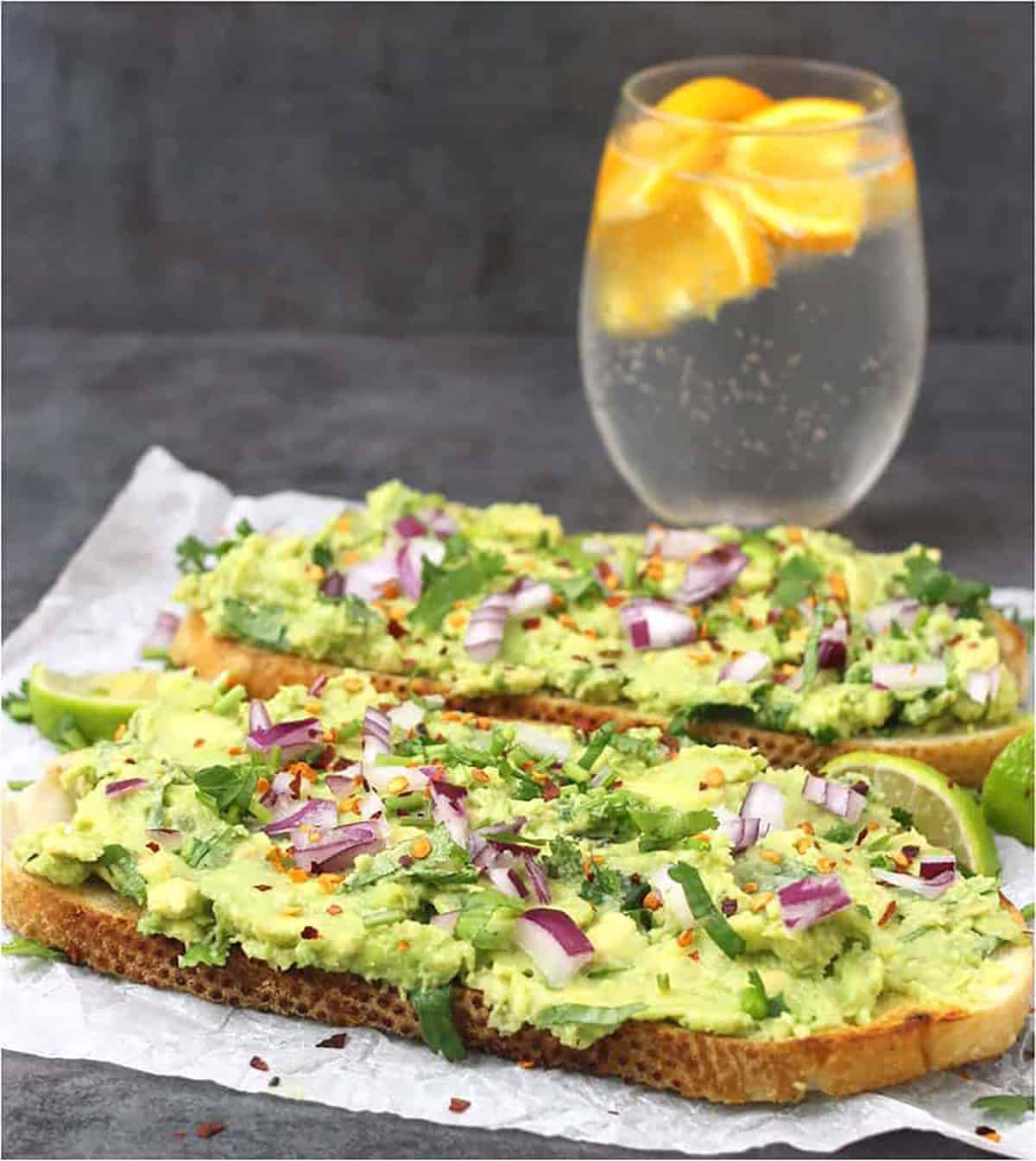Healthy meal for two, consisting of two large avocado toasts topped with onion and cilantro.