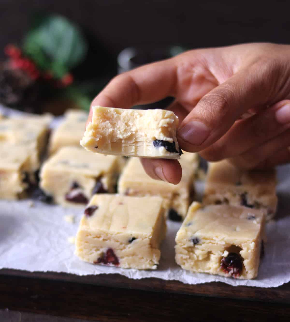 Holding a piece of holiday no bake white chocolate fudge 