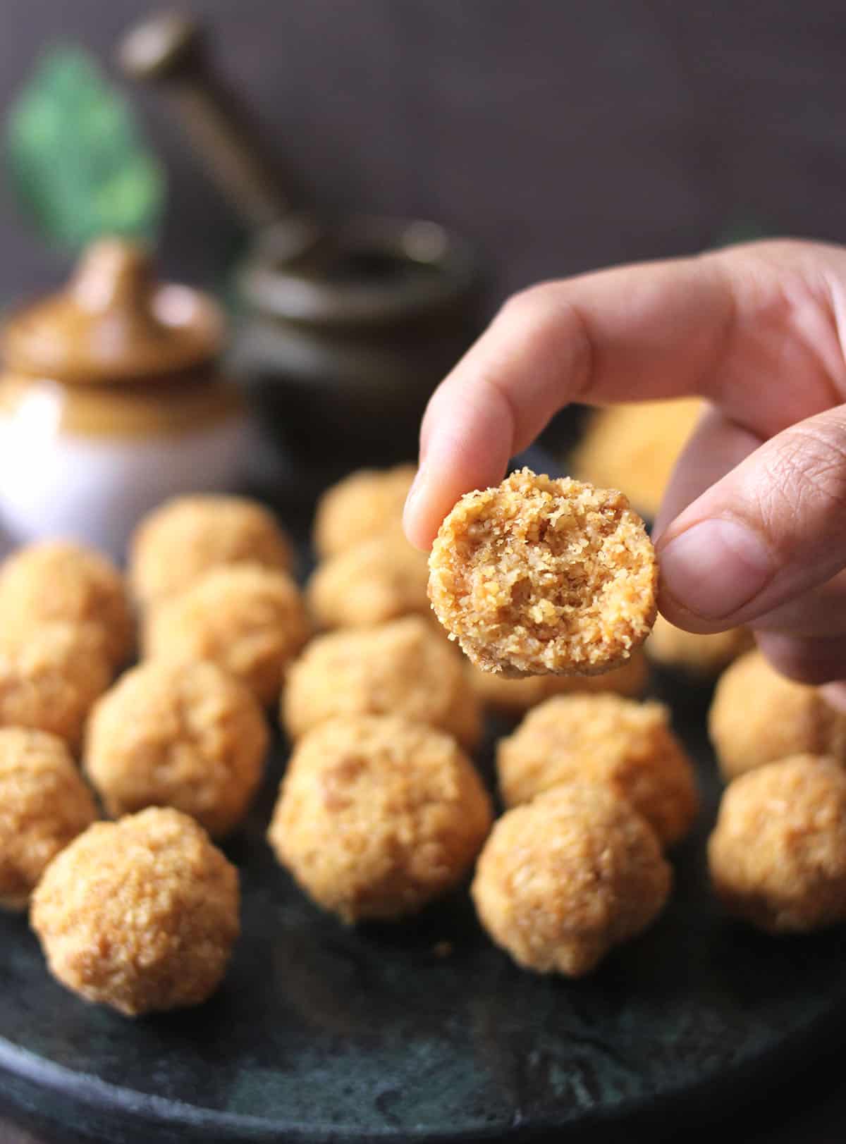 Holding 3 ingredient homemade coconut ladoo with jaggery, coconut laddu 