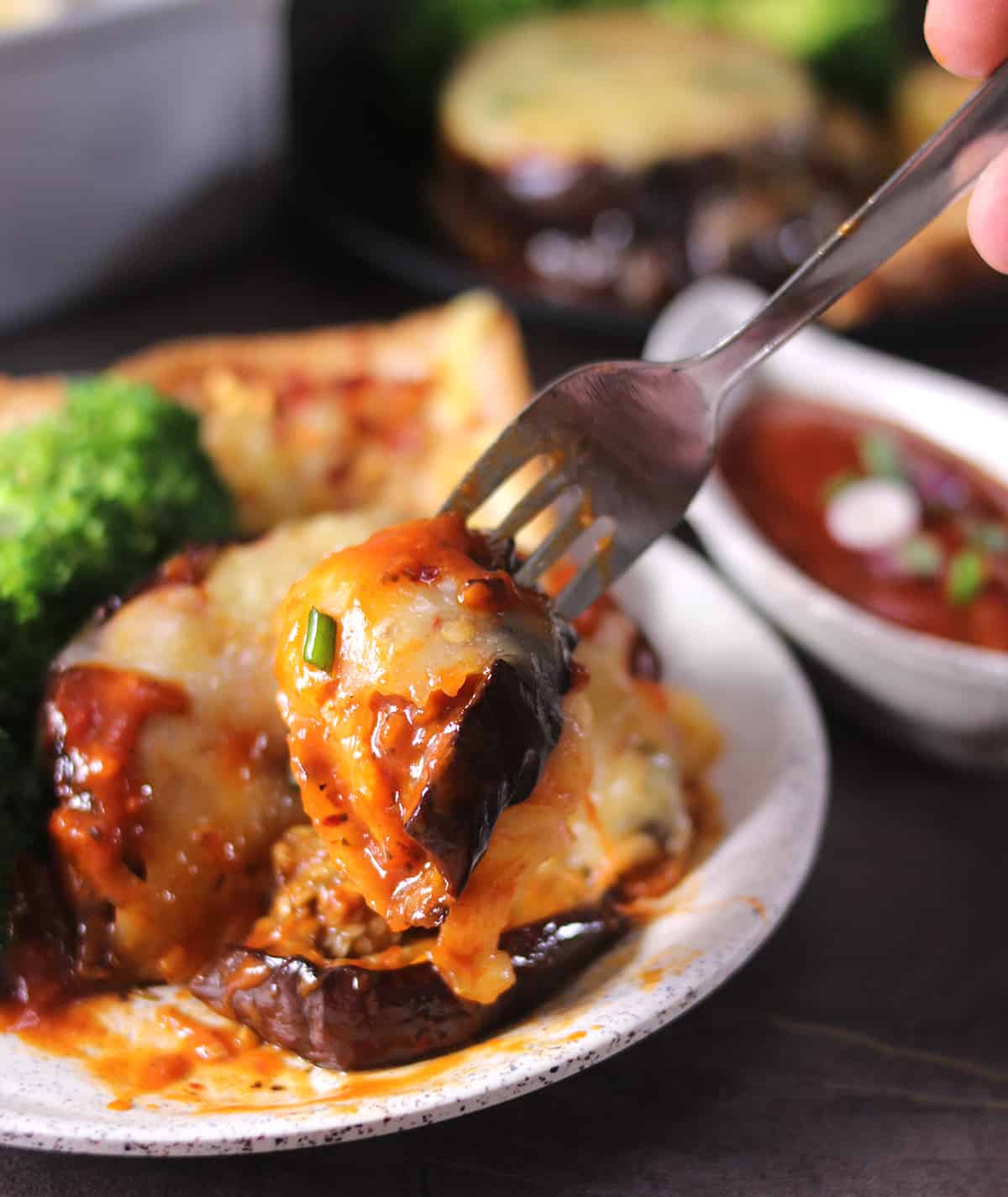 Holding a cheesy eggplant bite in fork