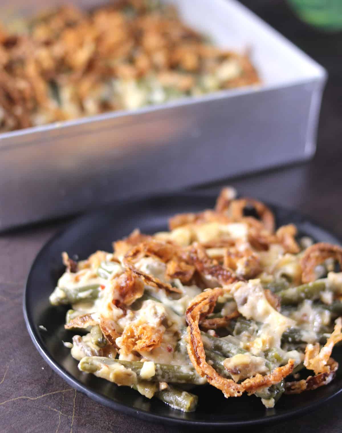 Serving green bea casserole on black plate garnished with crispy fried onions, best side dish for holiday 