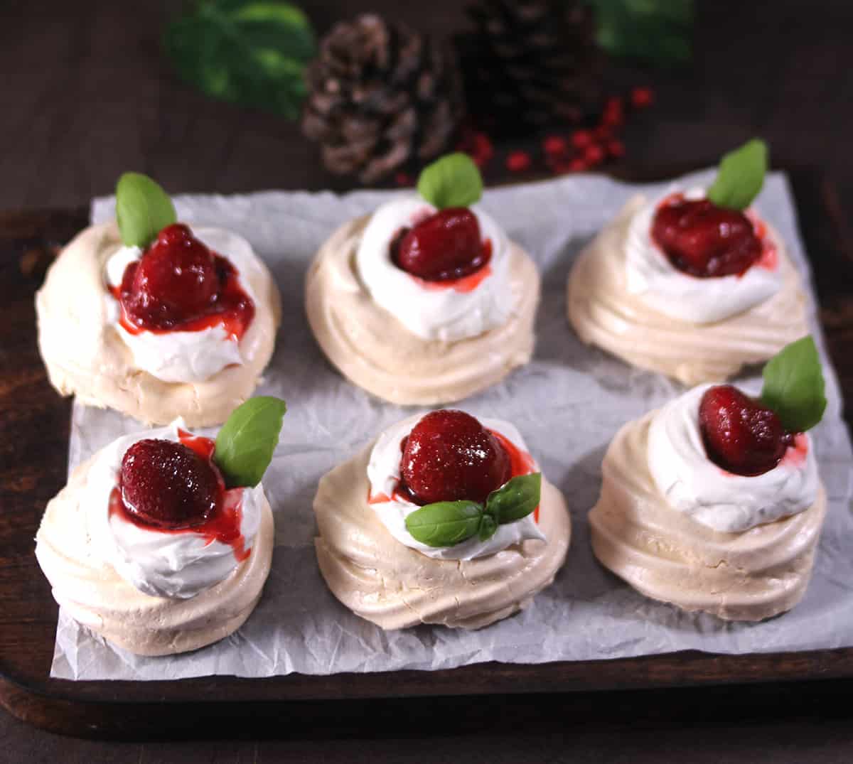 6 individual Pavlovas arranged on serving plate  with strawberry and whipped cream 
