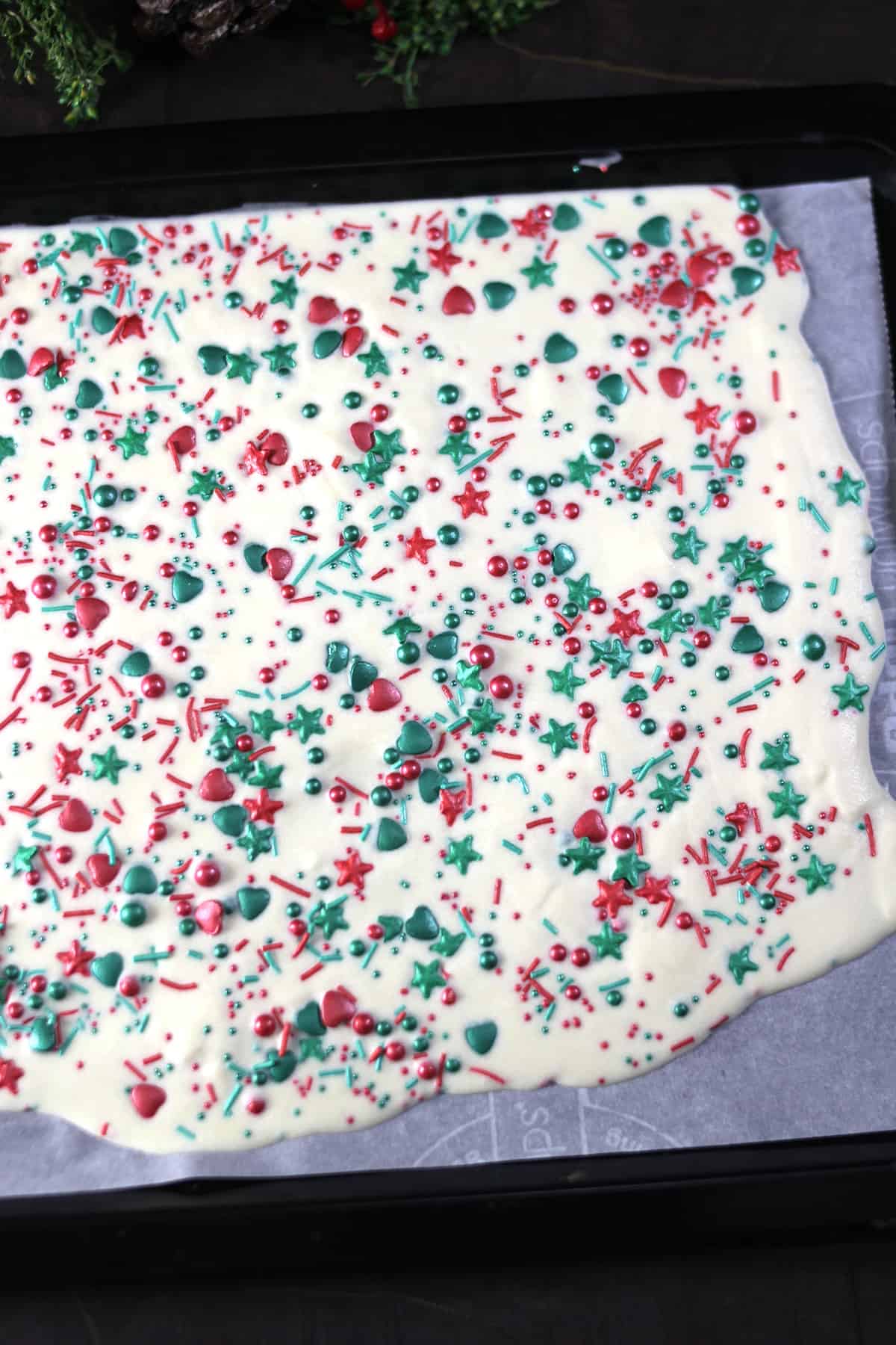 Top view of sheet of thin chocolate sheet (candy bark_ topped with Christmas sprinkles 