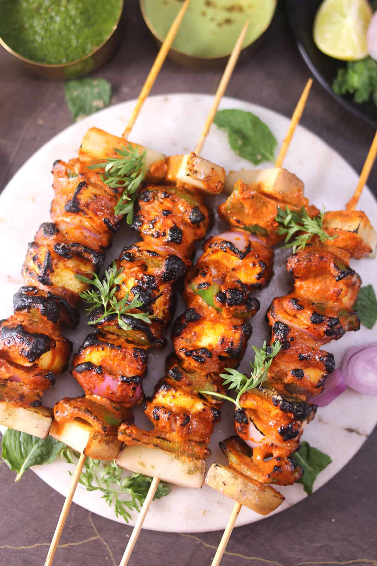 tandoori paneer tikka on skewers garnished with cilantro. 