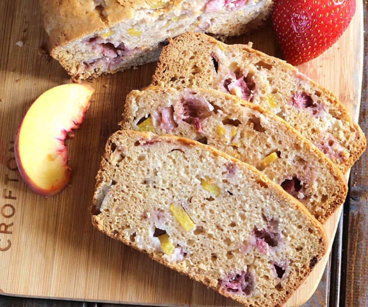 no knead strawberry and peach fruit bread slices served on a wooden board.