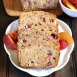fruit bread slices served in white plate, with a side of peach and strawberries slices.