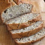 three slices and remaining loaf of simple and moist eggless banana bread on a wooden platter.