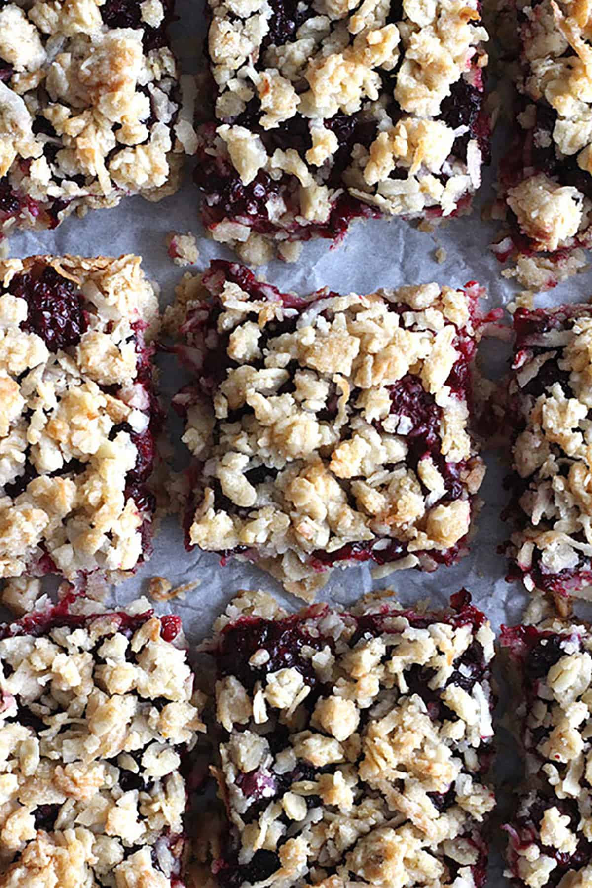 Freshly sliced Blackberry crumble bars served on parchment paper.