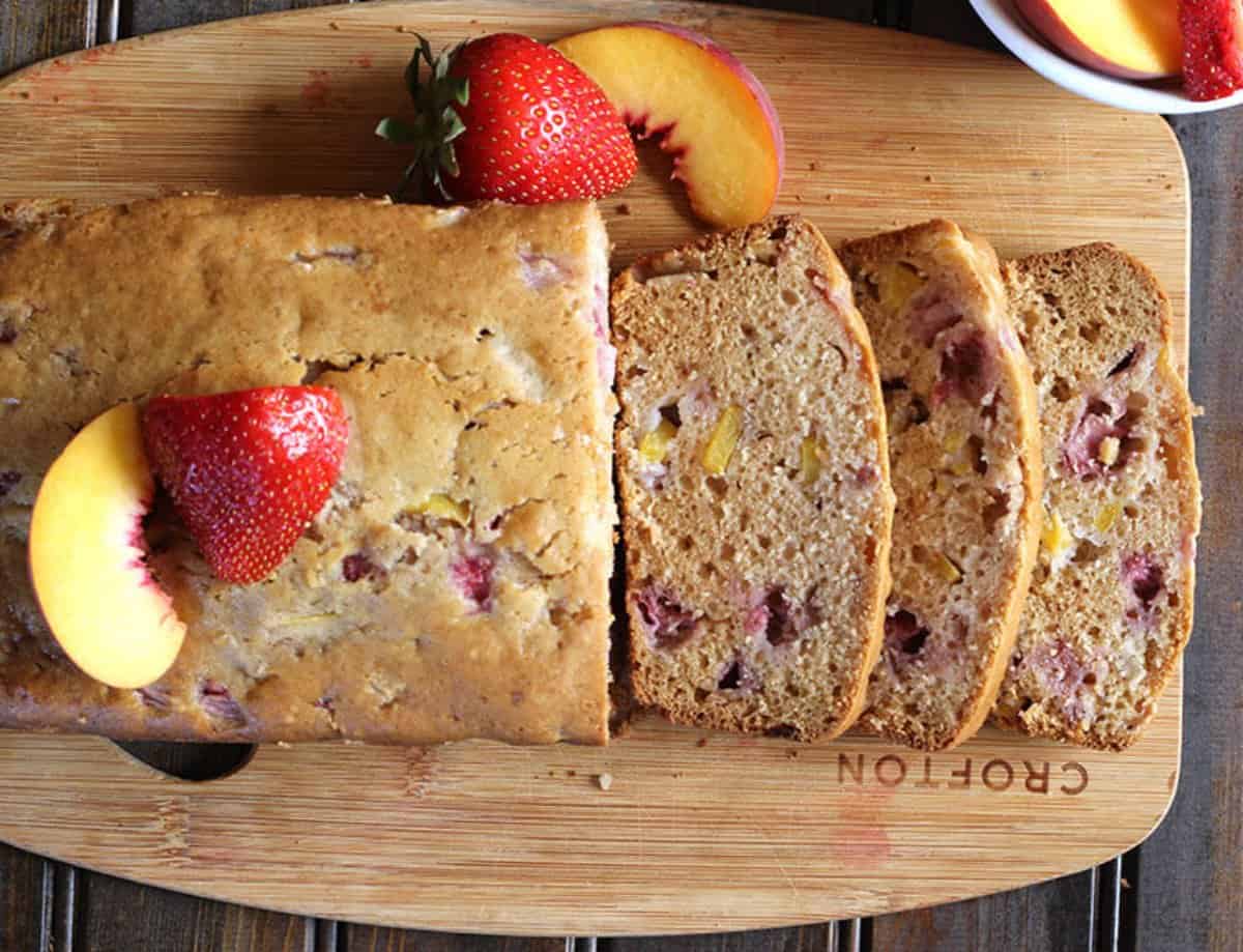 delicious fruit bread loaf with cut slices served on wooden board.