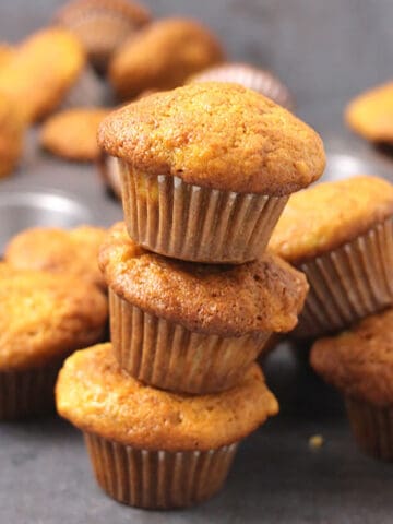 moist banana muffins stacked on each other, with many in the background.