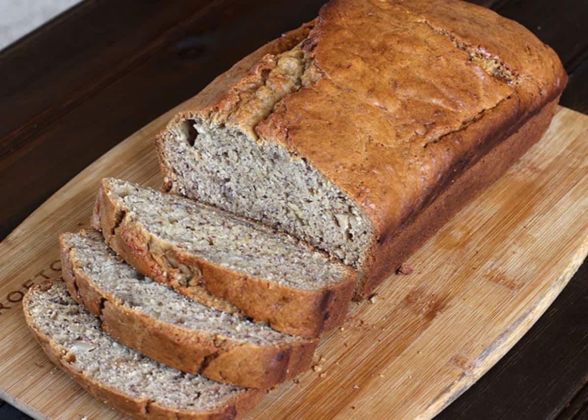 freshly sliced loaf of healthy eggless banana bread on a wooden board.