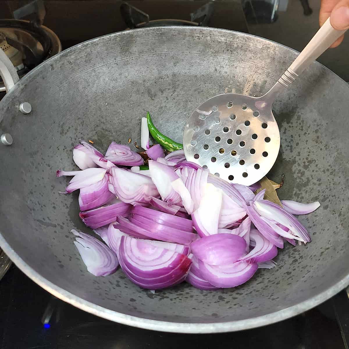 Sliced red onions added to the pan while preparing the best chicken pilaf.