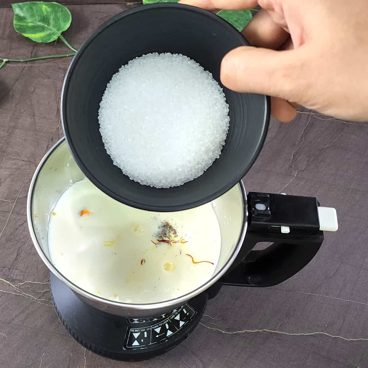 Adding sugar to the blender jar to sweeten the mango lassi.