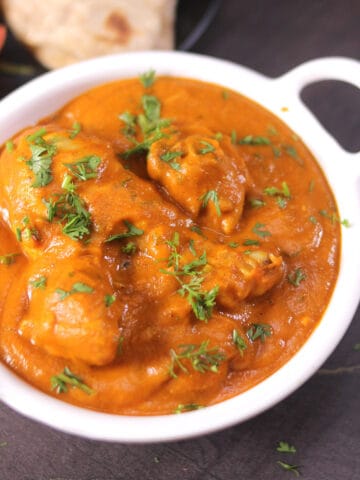 A bowl of best and easy, chicken handi curry garnished with coriander leaves.