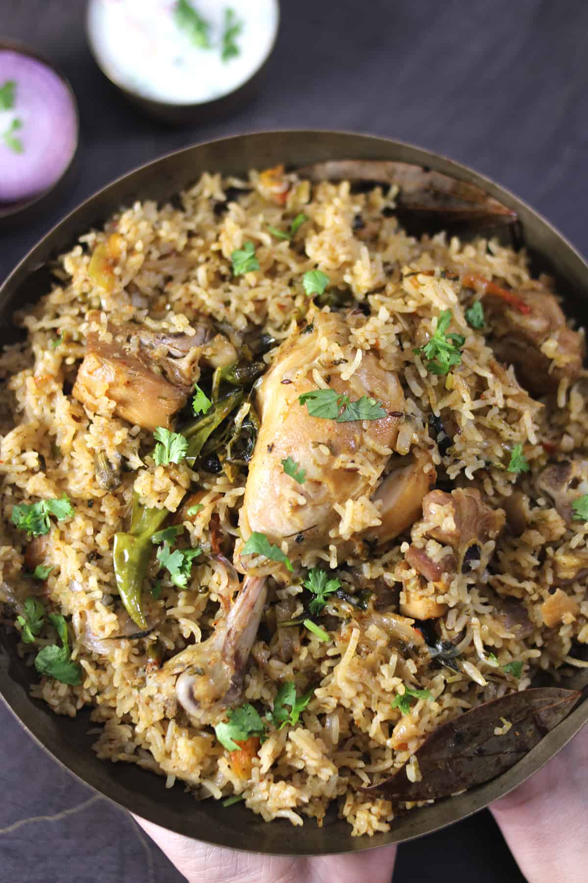 Best Chicken Pulao (Pilaf) with chicken drumstick served in a bronze plate, garnished with coriander leaves. 