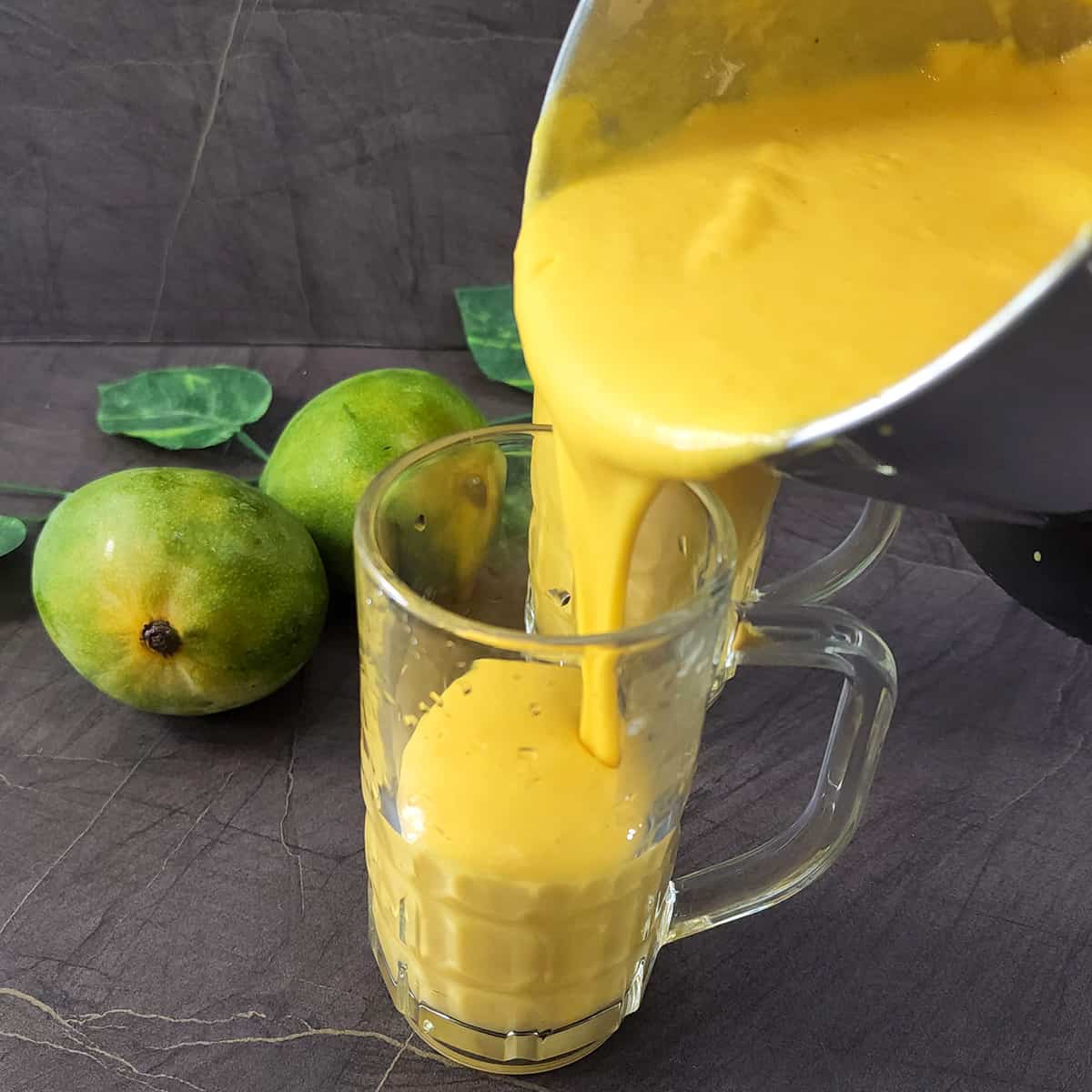Pouring the fresh mango lassi into serving glasses. 