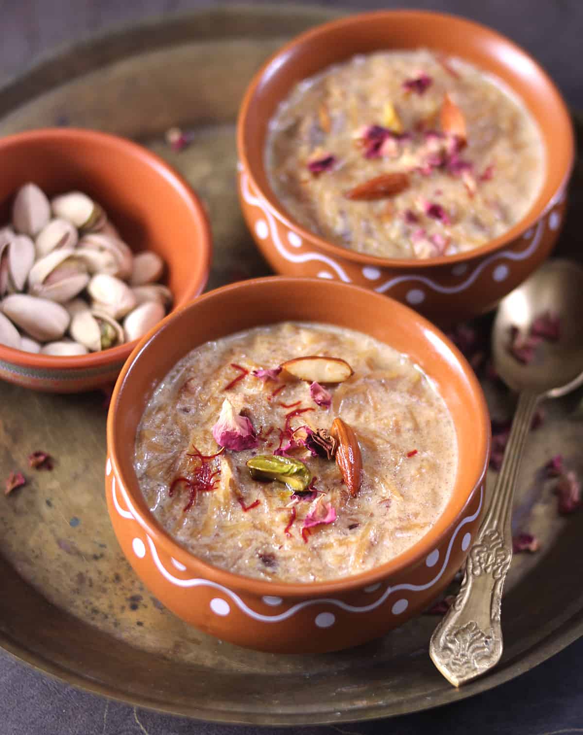 Sheer Khurma dessert garnished with rose, dried fruits and nuts, served warm in bowl. 