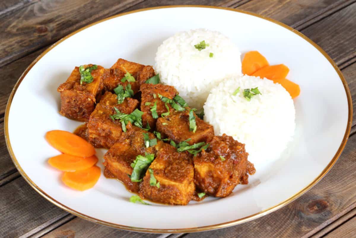 Crispy Fried Tofu Tossed in Spicy Thai Red Sauce and served in white ceramic plate along with cooked Rice.