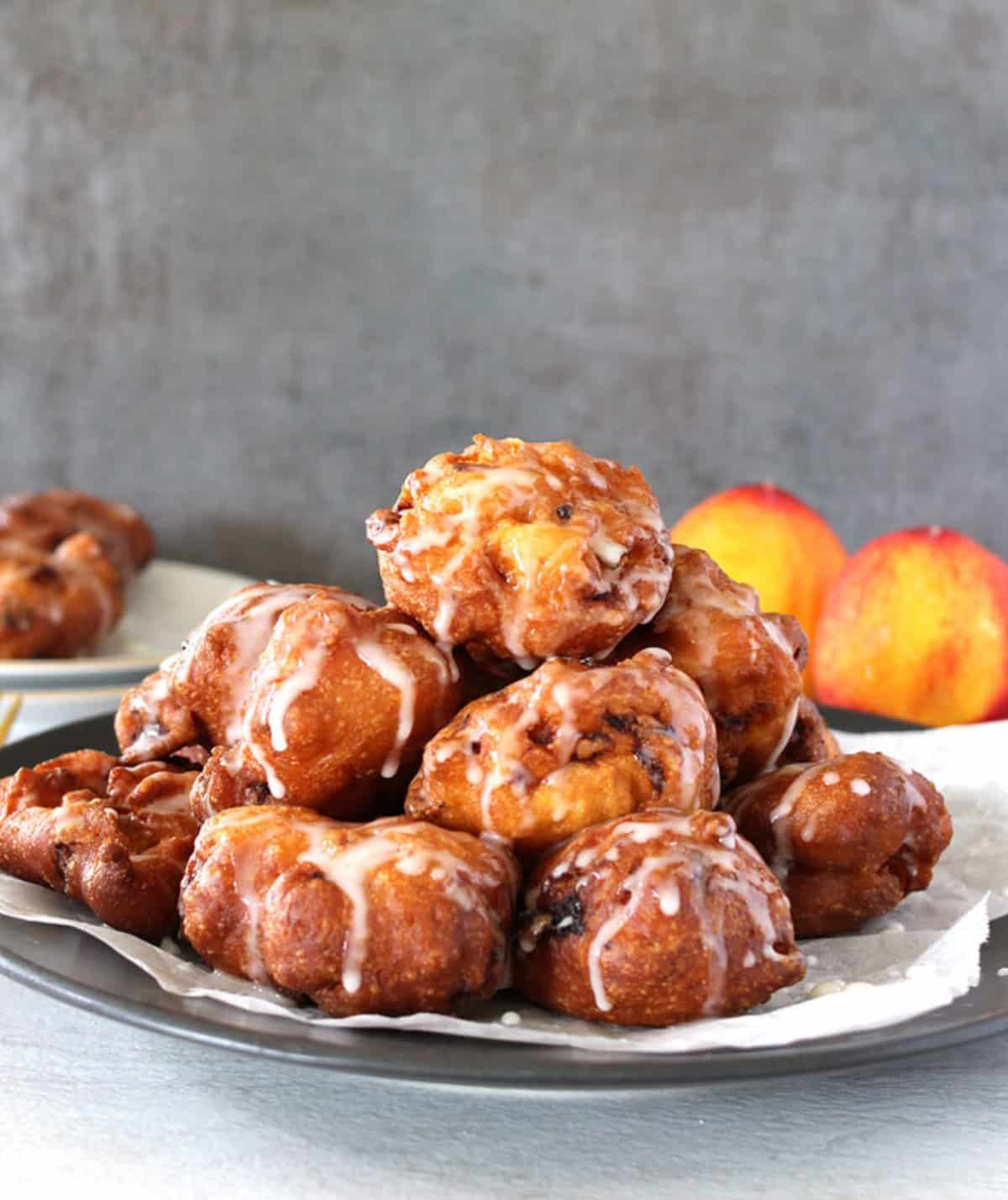 Best homemade peach fritters with a drizzle of sugar glaze in a large plate.
