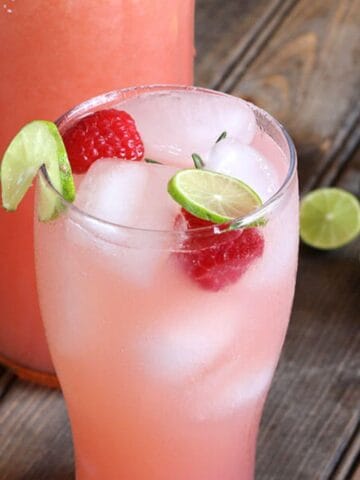 Quick and Refreshing Raspberry Lemonade served with ice cubes, whole raspberries, and lemon slices in a tall glass.