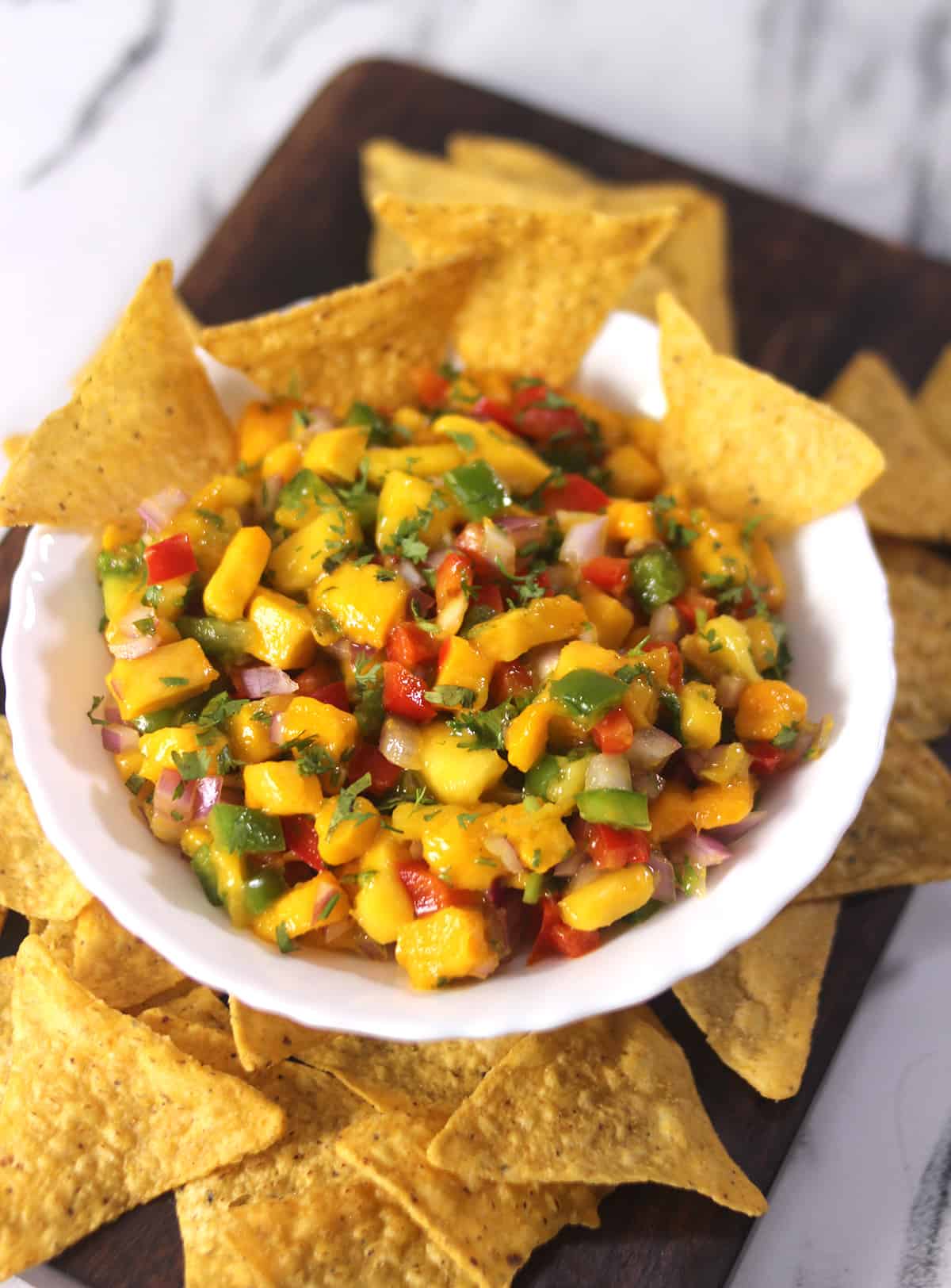 Fresh mango salsa in a white bowl with tortilla chips. 