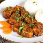 Quick and delicious fried tofu coated in a special Thai sauce and served with rice in a white ceramic plate.
