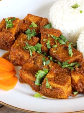 Quick and delicious fried tofu coated in a special Thai sauce and served with rice in a white ceramic plate.