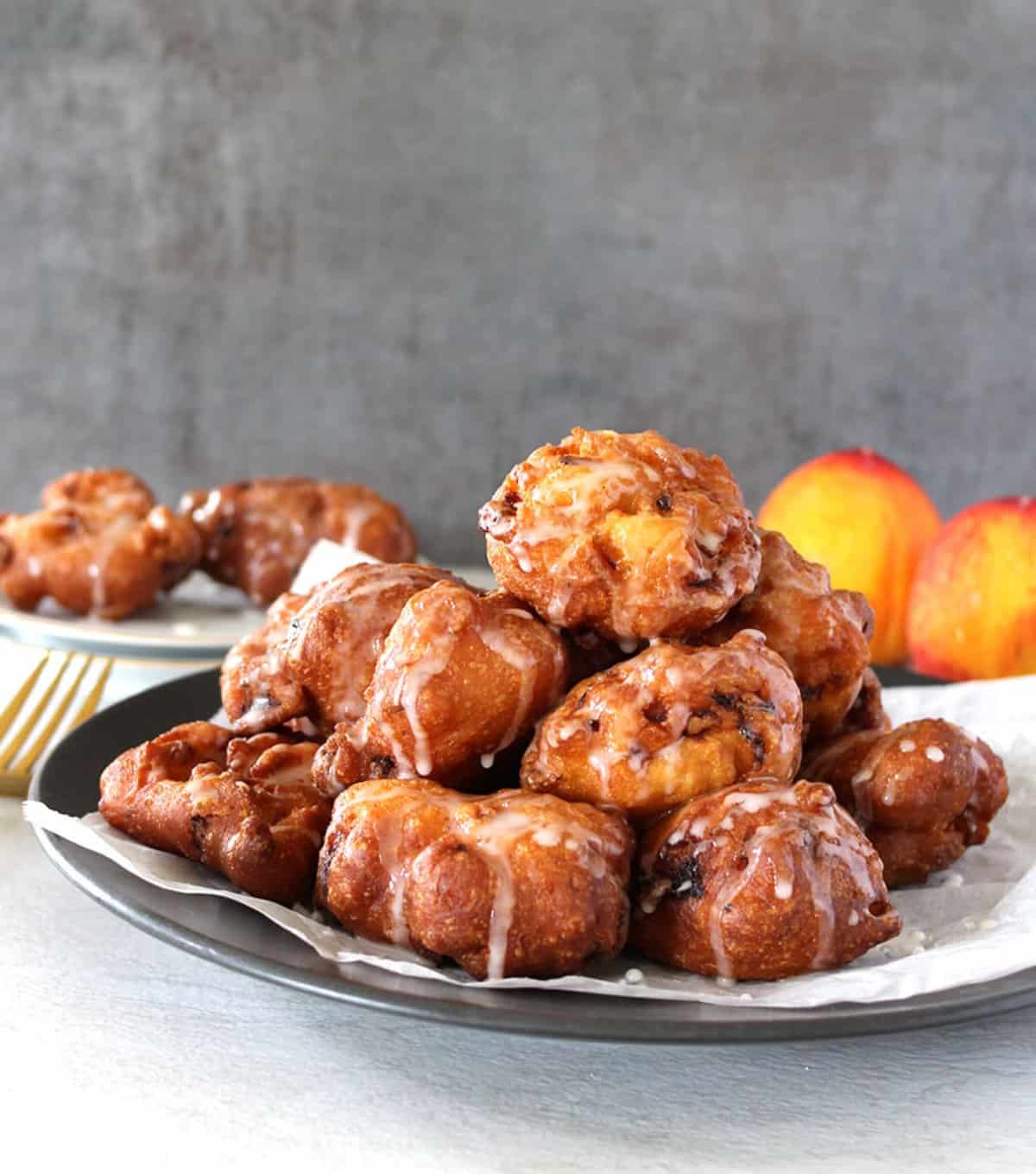 Easy homemade peach fritters with sugar glaze served in a large plate.