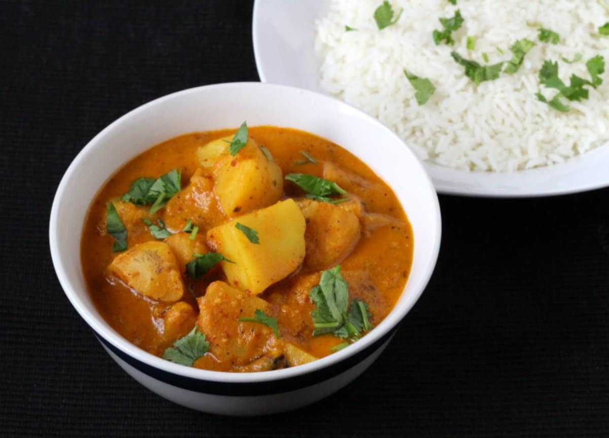 Tasty Goan Aloo Vindaloo served in a white ceramic bowl along with steamed jasmine rice.