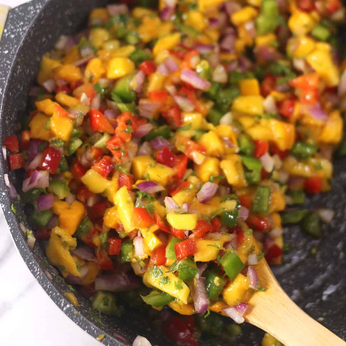 ladle full of combined ingredients for mango salsa. 