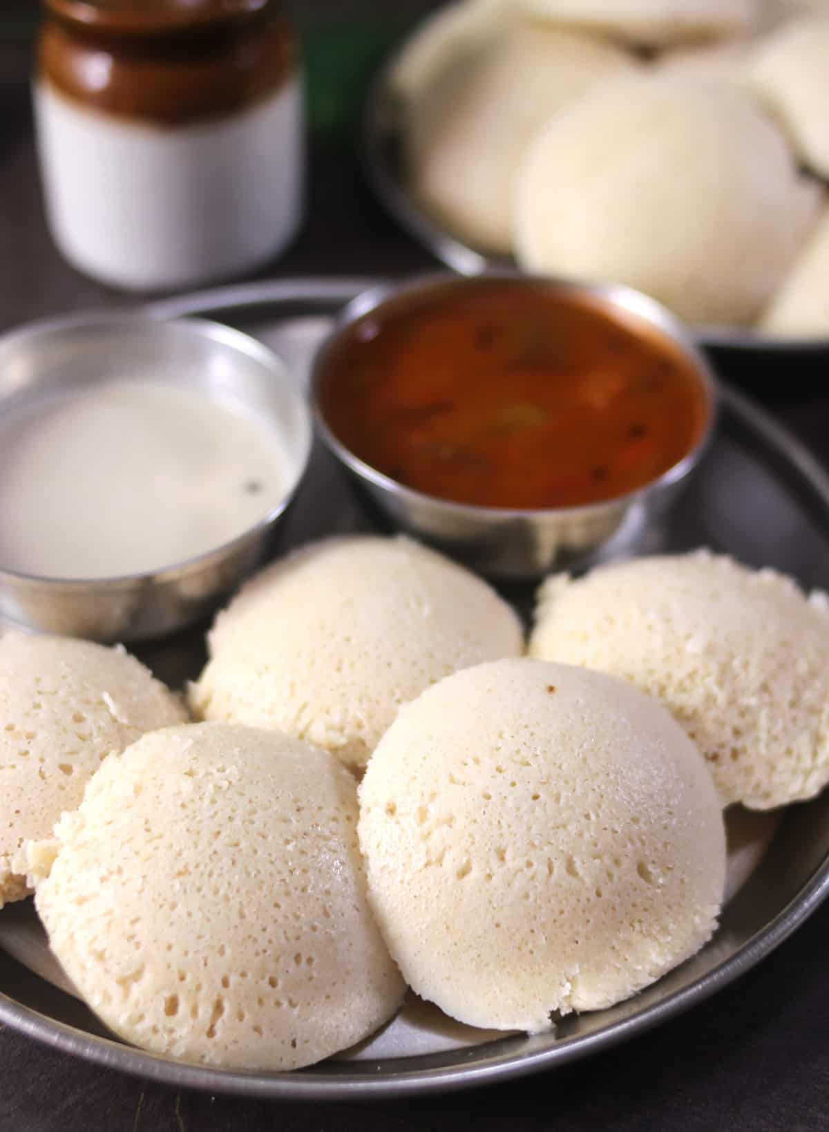 soft millet idli or quinoa idli on a plate served with sambar and coconut chutney. 