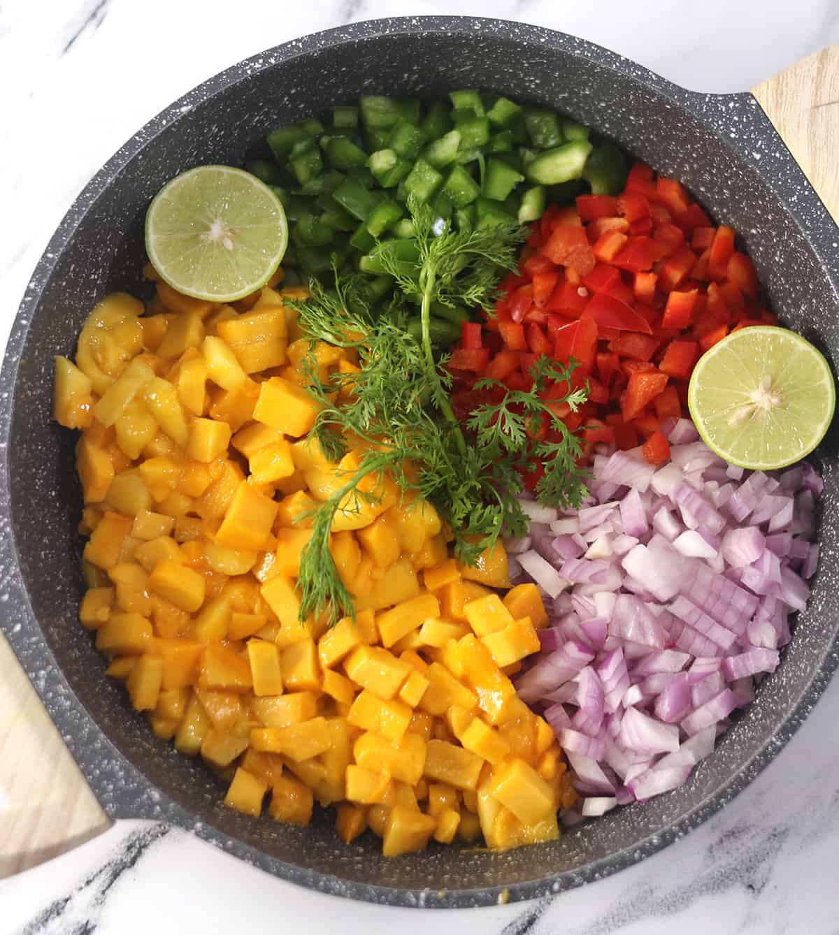 Finely chopped ingredients to make mango salsa in a carote pan. 