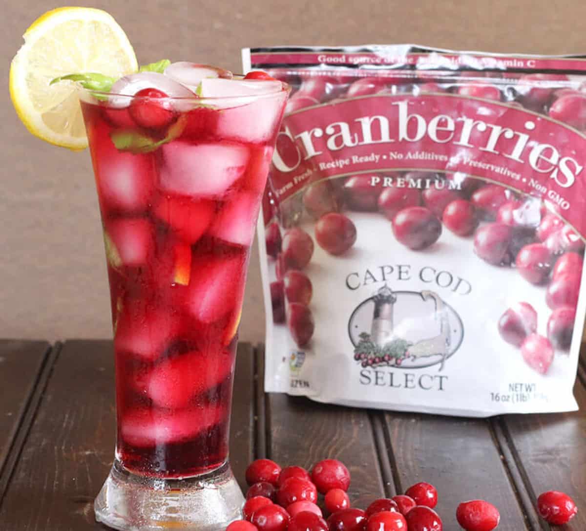 Homemade cranberry lemonade with real, fresh ingredients, served in a tall glass filled with ice and garnished with a slice of lemon.