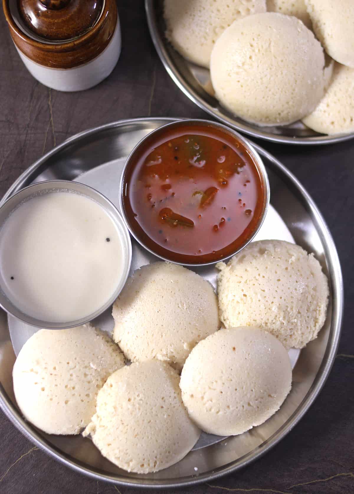 Healthy quinoa idli or millet idly on a plate served with tiffin sambhar and coconut chutney. 
