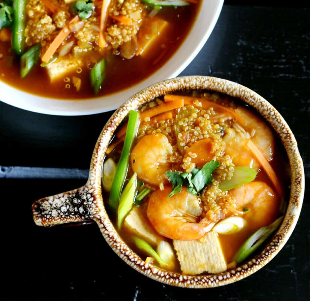 Healthy Quinoa Soup with Shrimp and Tofu served in a brown ceramic soup mug.