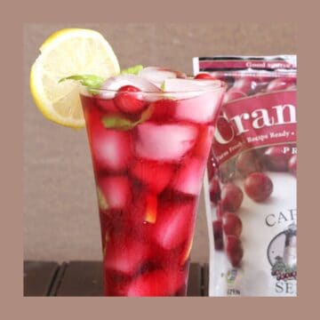 Sparkling cranberry lemonade served in a tall glass filled with ice and garnished with a slice of lemon.