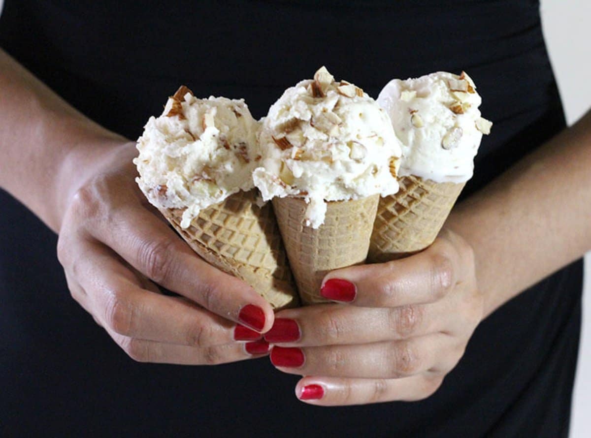 Three waffle cones with almond ice cream held in hand.