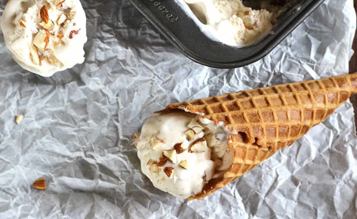 Quick and easy toasted almond ice cream in a waffle cone placed over parchment paper.